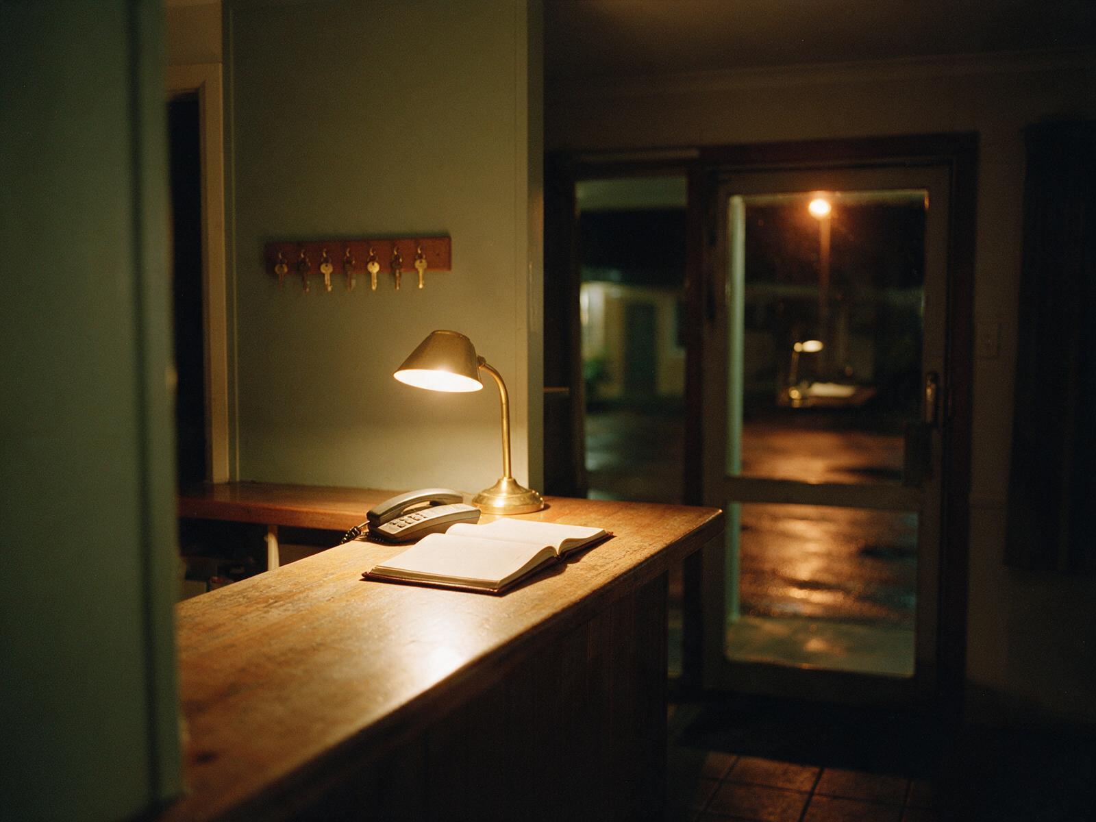 An empty motel reception lit by a single lamp late at night
